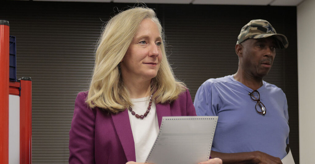 Abigail Spanberger in purple holds a ballot.