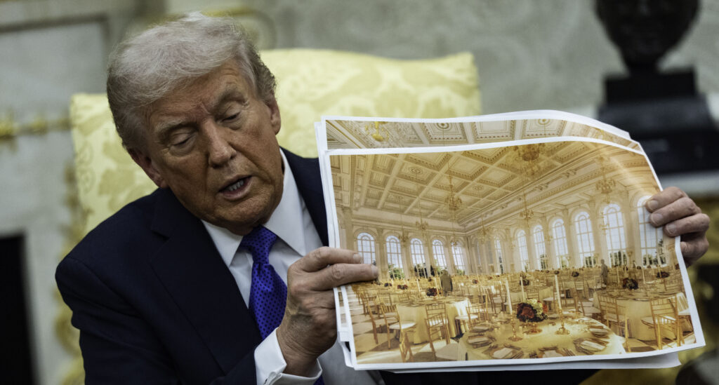 President Donald Trump speaks holding a photos of the new ballroom during a meeting with NATO Secretary General Mark Rutte in the Oval Office of the White House in Washington, DC on October 22, 2025.