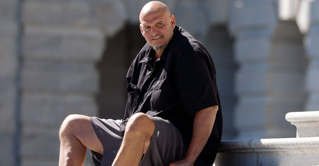Wearing shorts, Sen. John Fetterman, D-Pa., sits on the Capitol Steps.