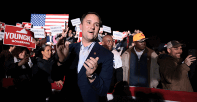Jason Miyares clapping at a nighttime rally in front of a crowd.