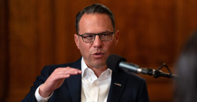 Josh Shapiro in a suit gestures in front of a microphone. Shapiro has condemned Jay Jones' tweets but hasn't called for him to drop out of the race