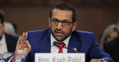 FBI Director Kash Patel, in a blue suit, makes the "OK" sign