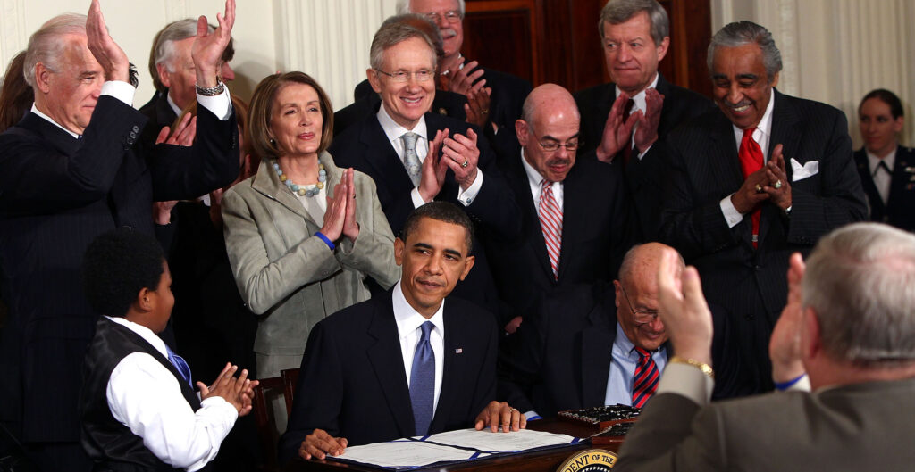 President Barack Obama is applauded by fellow Democrats after signing the Affordable Care Act into law at the White House on March 23, 2010.