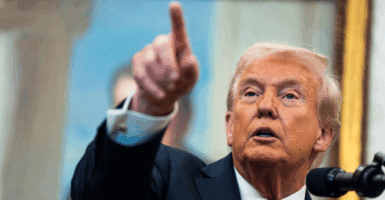 President Donald Trump points to the press answering questions in the oval office.