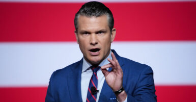 Defense chief Pete Hegseth speaks in front of an American flag backdrop.