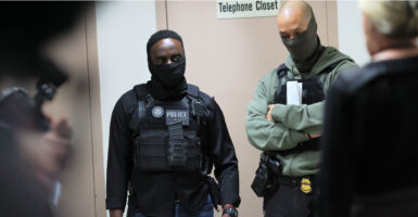 Two federal agents stand in front of a telephone closet.