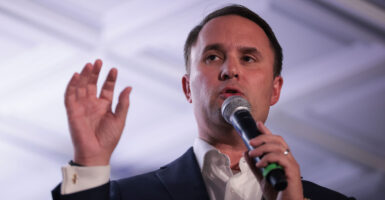 Virginia Republican Attorney General Jason Miyares with a raised hand and a microphone speaking to an audience