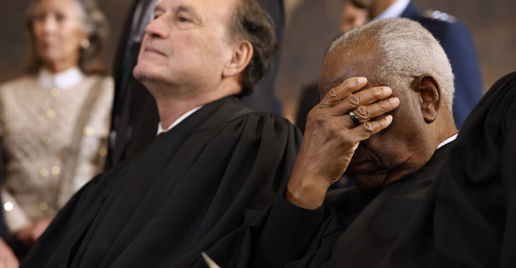 U.S. Supreme Court Associate Justices Samuel Alito (L) and Clarence Thomas wait for their opportunity to leave the stage.