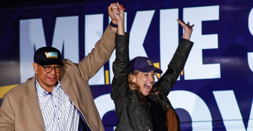 Democrat New Jersey gubernatorial candidate Mikie Sherrill, right, and Dr. Dale Caldwell with arms raised at a campaign event