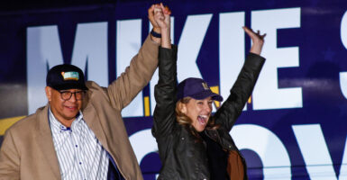 Democrat New Jersey gubernatorial candidate Mikie Sherrill, right, and Dr. Dale Caldwell with arms raised at a campaign event