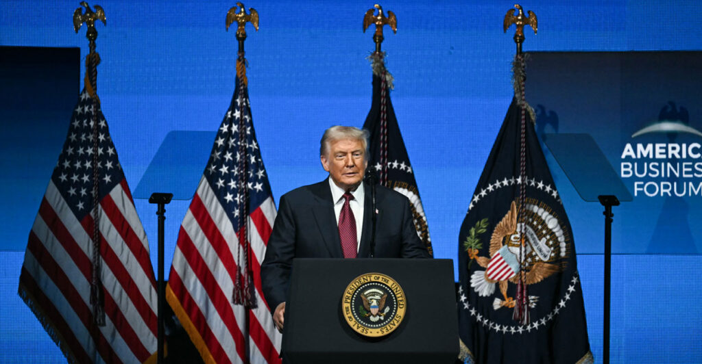 With U.S. flags as a backdrop, President Donald Trump speaks at the American Business Forum in Miami on Wednesday.