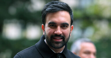 Zohran Mamdani stands up outdoors and looks straight ahead.