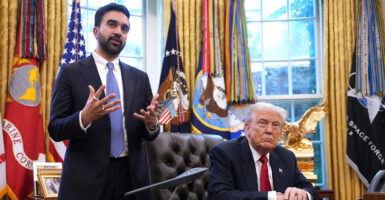 Zohran Mamdani stands in the White House and gestures with both his hands as he talks to reporters as Donald Trump looks on.