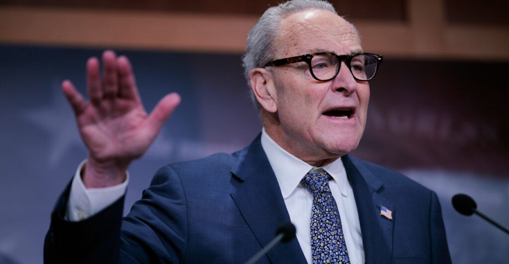 Chuck Schumer with hand raised.