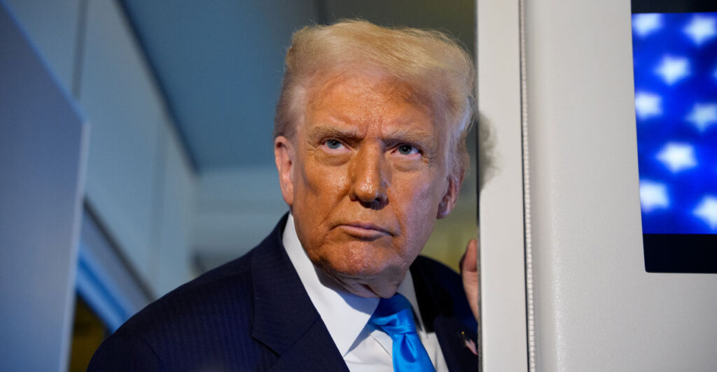 Donald Trump leans against a door frame on Air Force One.