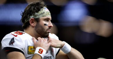 Tampa Bay Buccaneers quarterback Baker Mayfield holds onto the front of his jersey and shoulder pads.