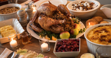 A Thanksgiving feast is spread across a table, with mouthwatering turkey in the center.