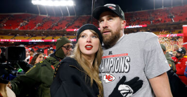 Taylor Swift holds onto Travis Kelce on the field after a Kansas City Chiefs game.