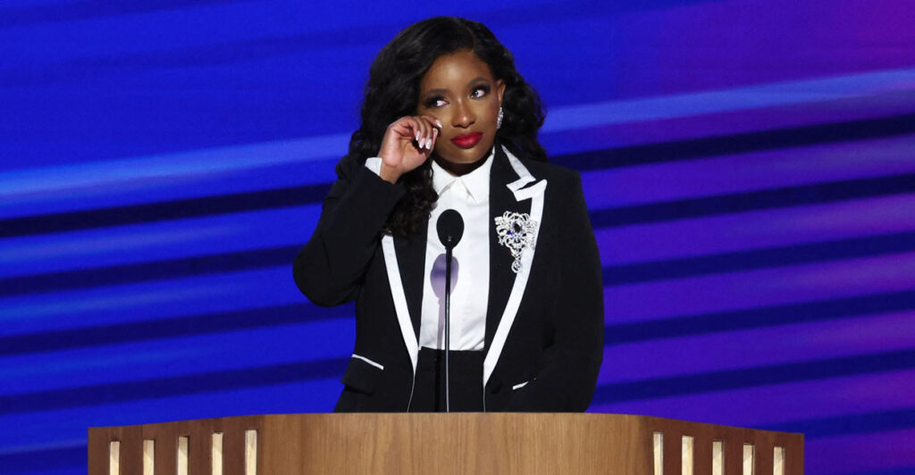 Jasmine Crockett, in a black-and-white suit, wipes away a tear while addressing the DNC convention.