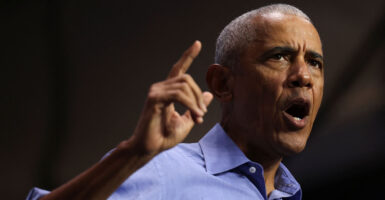 Barack Obama in a blue shirt pointing with his mouth open.