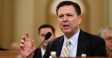 James Comey, with his hand raised, testifies before Congress.