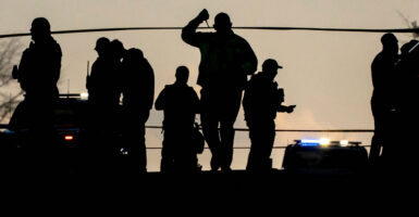 Law enforcement members are silhouetted as they gather in a cordoned-off area after two National Guard members were reportedly shot near the White House in Washington, D.C., U.S., November 26, 2025. REUTERS/Nathan Howard