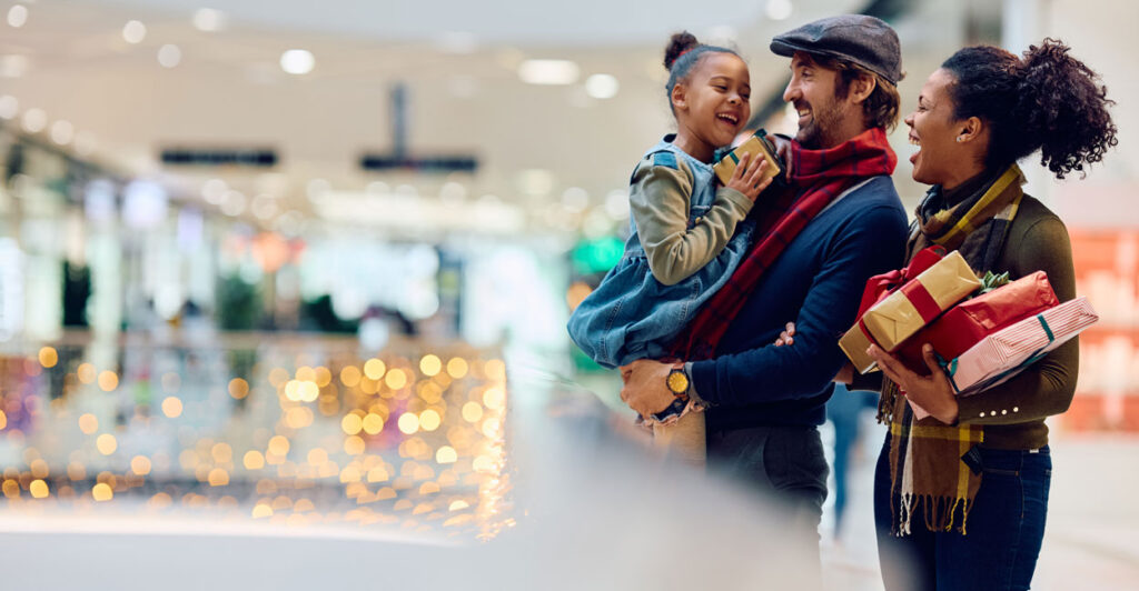Mixed race couple with adorable child go Christmas shopping in a mall.