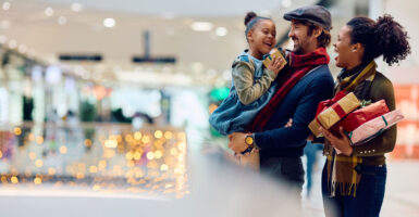 Mixed race couple with adorable child go Christmas shopping in a mall.
