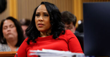 Fani Willis in a red outfit sits in a courtroom.