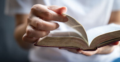 Close up of white hand flipping pages of a Bible.