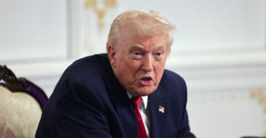 President Trump, leaning forward, speaks.