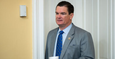 Austin Scott holds a cup of coffee in the house rules committee.