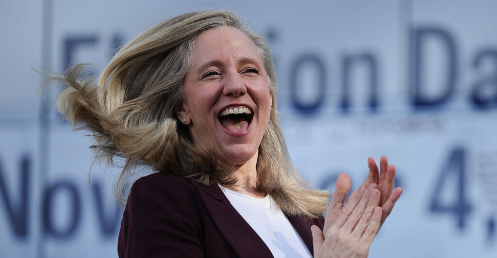 Abigail Spanberger laughs and claps. The Associated Press predicts she will win the Virginia governor's race