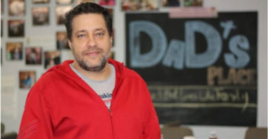 Pastor Chris Avell stands in front of a "Dad's Place" sign.