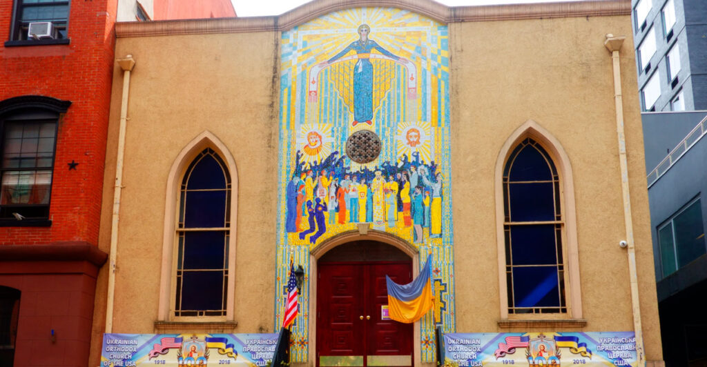 Pray for Ukraine sign on Ukrainian Orthodox Church exterior entrance with mosaics.