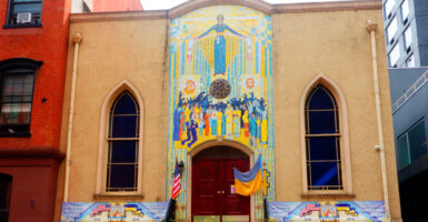 Pray for Ukraine sign on Ukrainian Orthodox Church exterior entrance with mosaics.