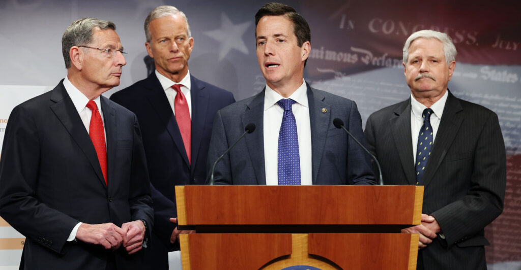 Sens. John Barrasso, Bernie Moreno, John Hoeven, and Senate Majority Leader John Thune stand at a podium to speak.