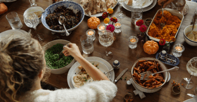Teenage girl having food while sitting at dining table during Thanksgiving
