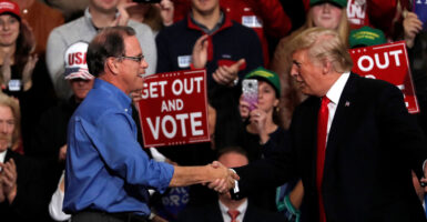 President Donald Trump shakes hands with Mike Braun during a campaign rall.