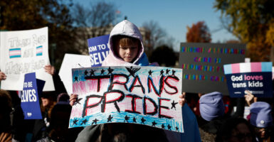 Child holding a sign that says "trans pride" at the Supreme Court.