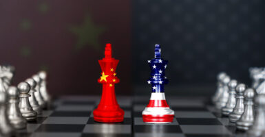 Two chess pieces sit on a chess board. One looks like the China flag and the other looks like the USA flag.