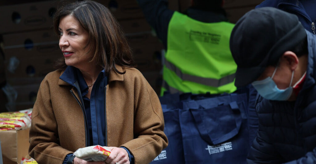 Kathy Hochul stands in a market holding packaged food in her hand.