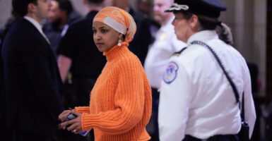 Ilmar Omar stands in a hallway with a cell phone in her left hand.