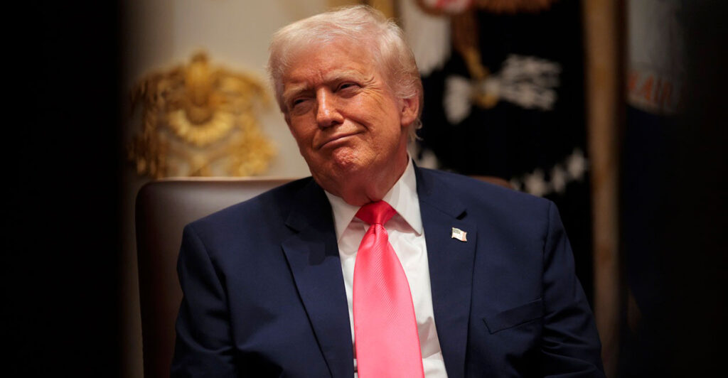 Donald Trump is seated and looking to his left as he makes a facial expression.