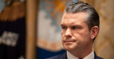 Pete Hegseth turns his head to his right during a meeting.