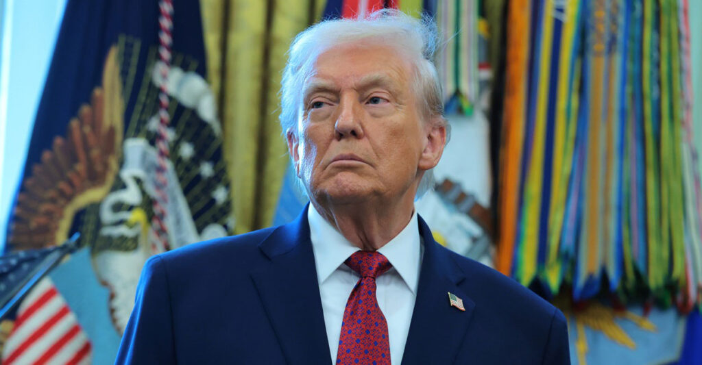 Donald Trump stands during a press conference and looks to his right.