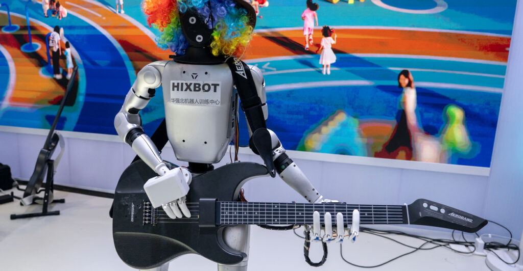 A silver Mexbot Robot in rainbow-colored wig holds a black guitar.