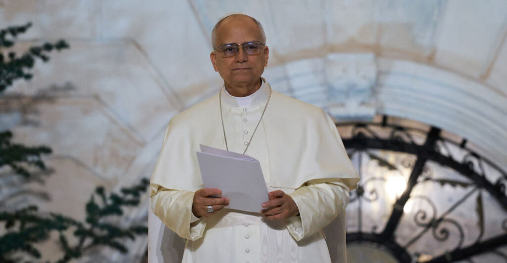 Pope Leo XIV stands, holding a white folder.