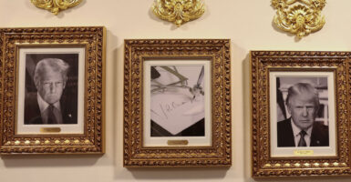 A portrait of the Joe Biden autopen flanked by portraits of Donald Trump.