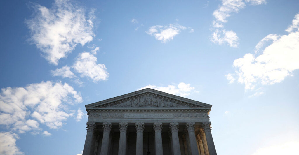 Top half of the U.S. Supreme Court building against a blue sky with a few scattered clouds.